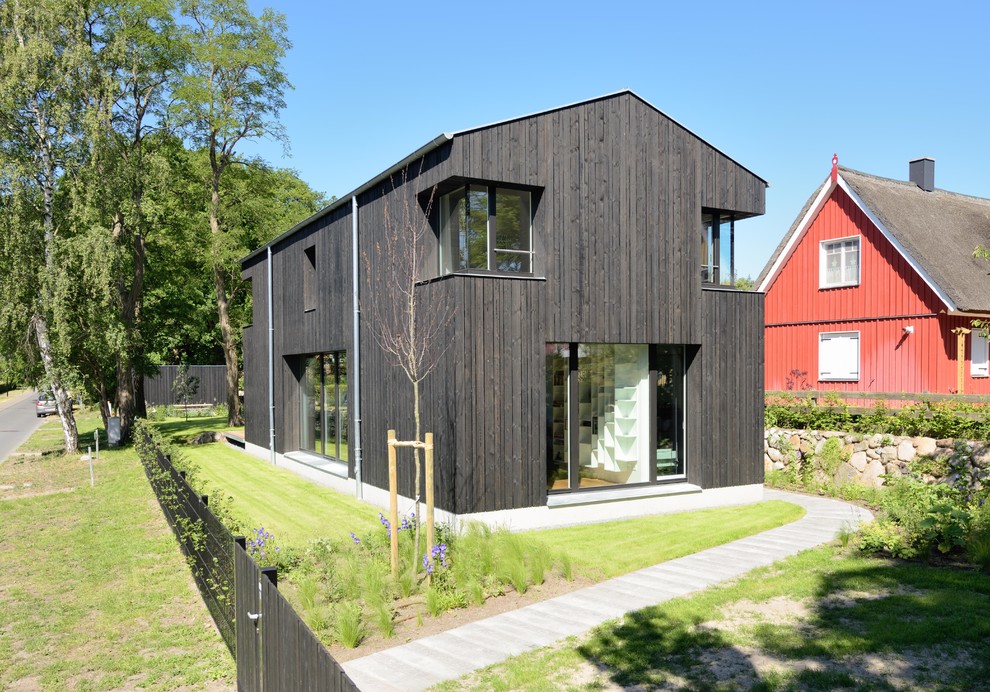 Inspiration for a large scandinavian two-storey black exterior in Other with wood siding and a gable roof.