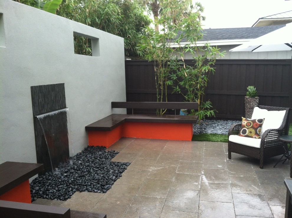 Small modern backyard patio in Jacksonville with a water feature and natural stone pavers.