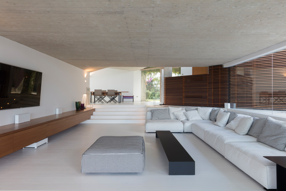 Esempio di un ampio soggiorno moderno aperto con pareti bianche e TV a parete