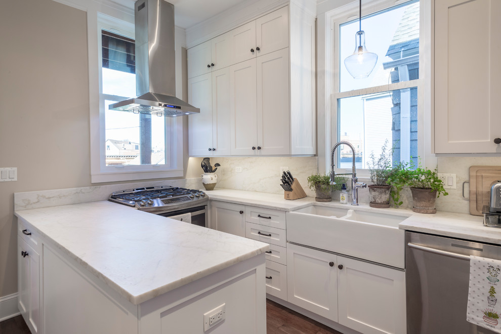Inspiration for a mid-sized transitional galley medium tone wood floor and brown floor eat-in kitchen remodel in Chicago with a farmhouse sink, shaker cabinets, white cabinets, marble countertops, white backsplash, stone slab backsplash, stainless steel appliances and a peninsula