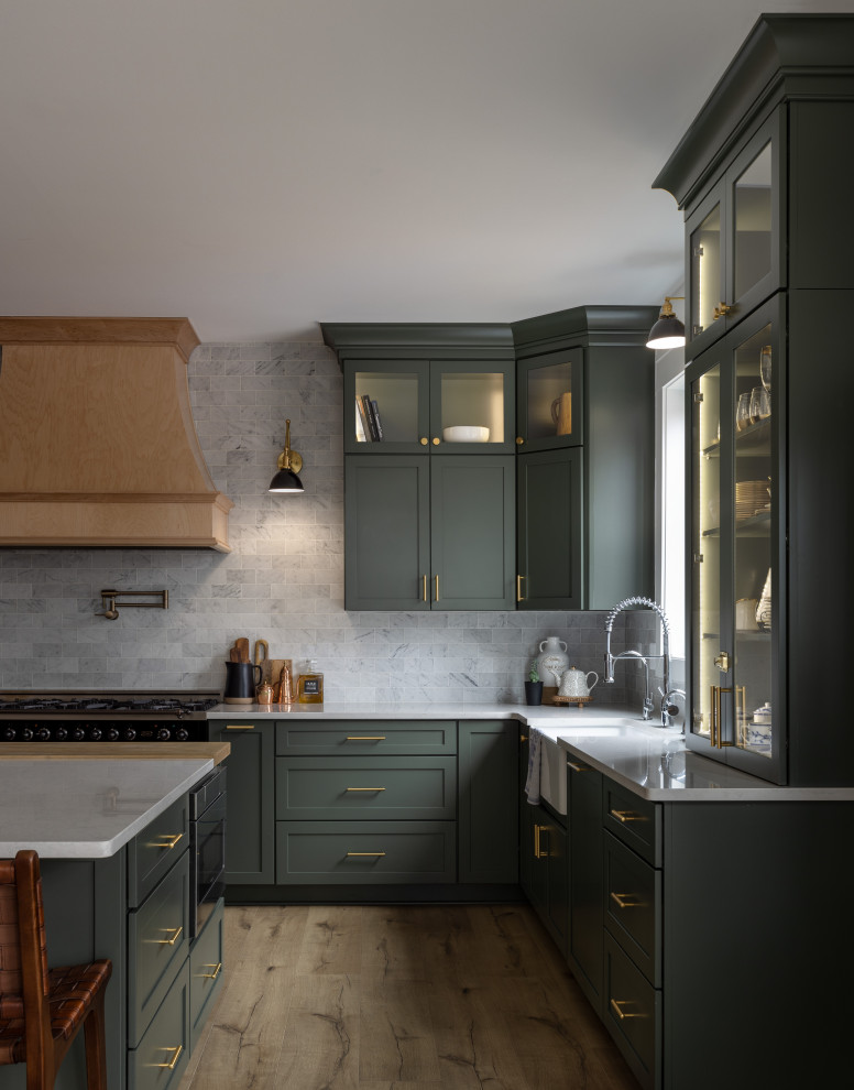 Example of a large classic u-shaped light wood floor and beige floor open concept kitchen design in Detroit with a farmhouse sink, shaker cabinets, green cabinets, quartz countertops, white backsplash, marble backsplash, stainless steel appliances, an island and white countertops
