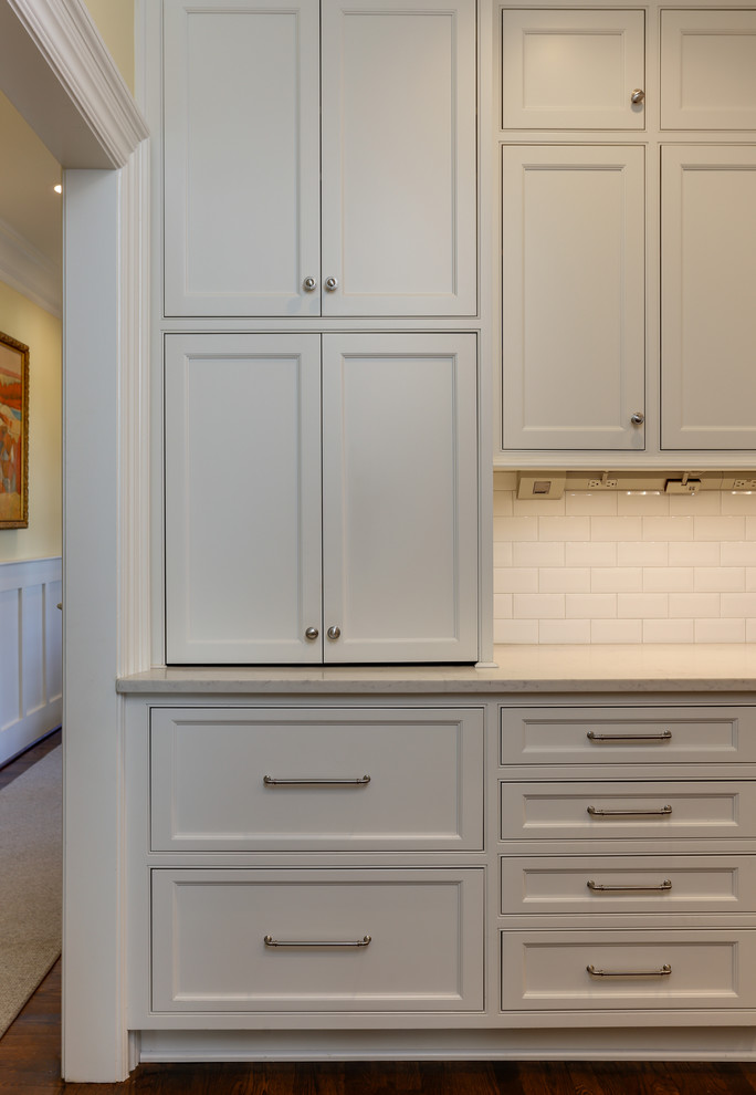 Photo of a mid-sized traditional galley separate kitchen in Raleigh with an undermount sink, beaded inset cabinets, white cabinets, quartz benchtops, white splashback, ceramic splashback, stainless steel appliances and medium hardwood floors.