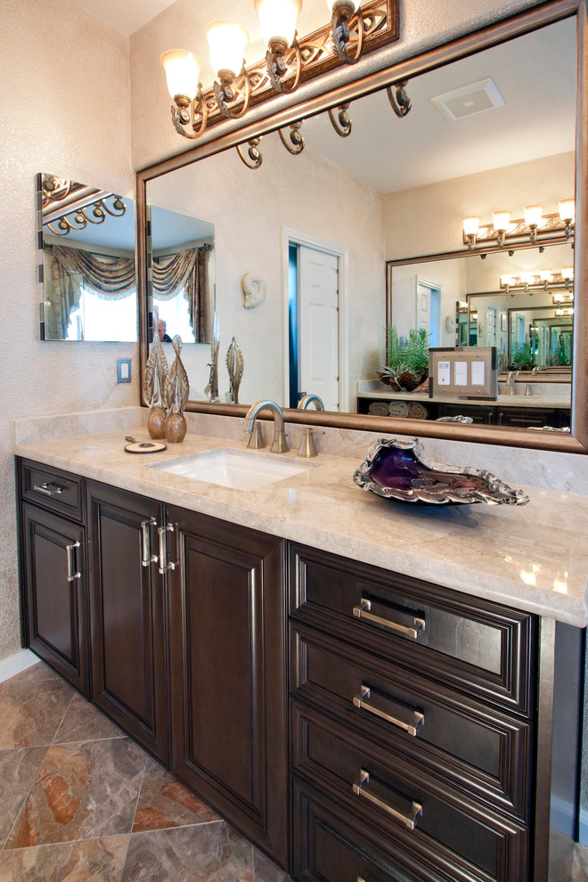 This is an example of a mid-sized modern master bathroom in San Francisco with raised-panel cabinets, black cabinets, a corner tub, a corner shower, a one-piece toilet, beige tile, ceramic tile, beige walls, ceramic floors, an undermount sink, quartzite benchtops, beige floor and a hinged shower door.