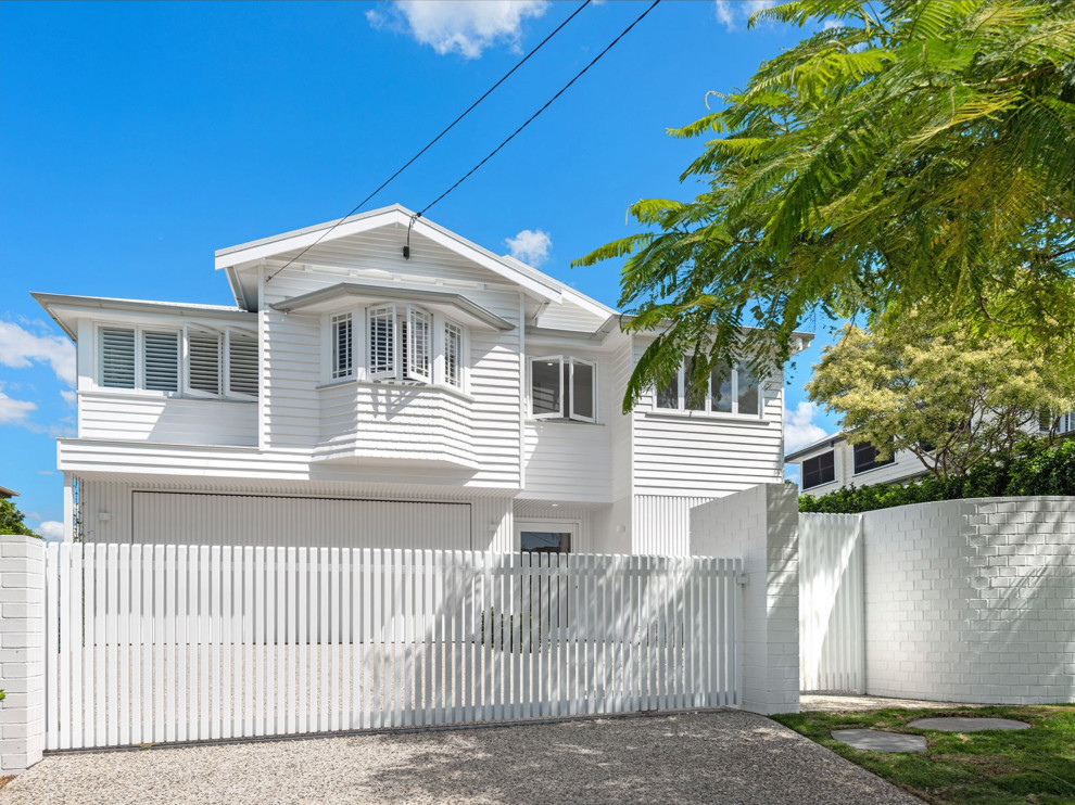 This is an example of a large contemporary two-storey white house exterior in Brisbane with wood siding, a gable roof and a metal roof.