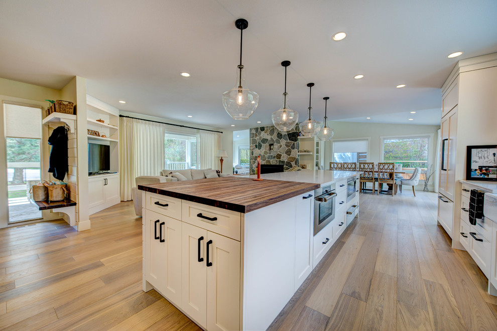 Inspiration for a mid-sized transitional l-shaped medium tone wood floor and beige floor eat-in kitchen remodel in Vancouver with an undermount sink, shaker cabinets, white cabinets, quartz countertops, white backsplash, ceramic backsplash, stainless steel appliances and an island