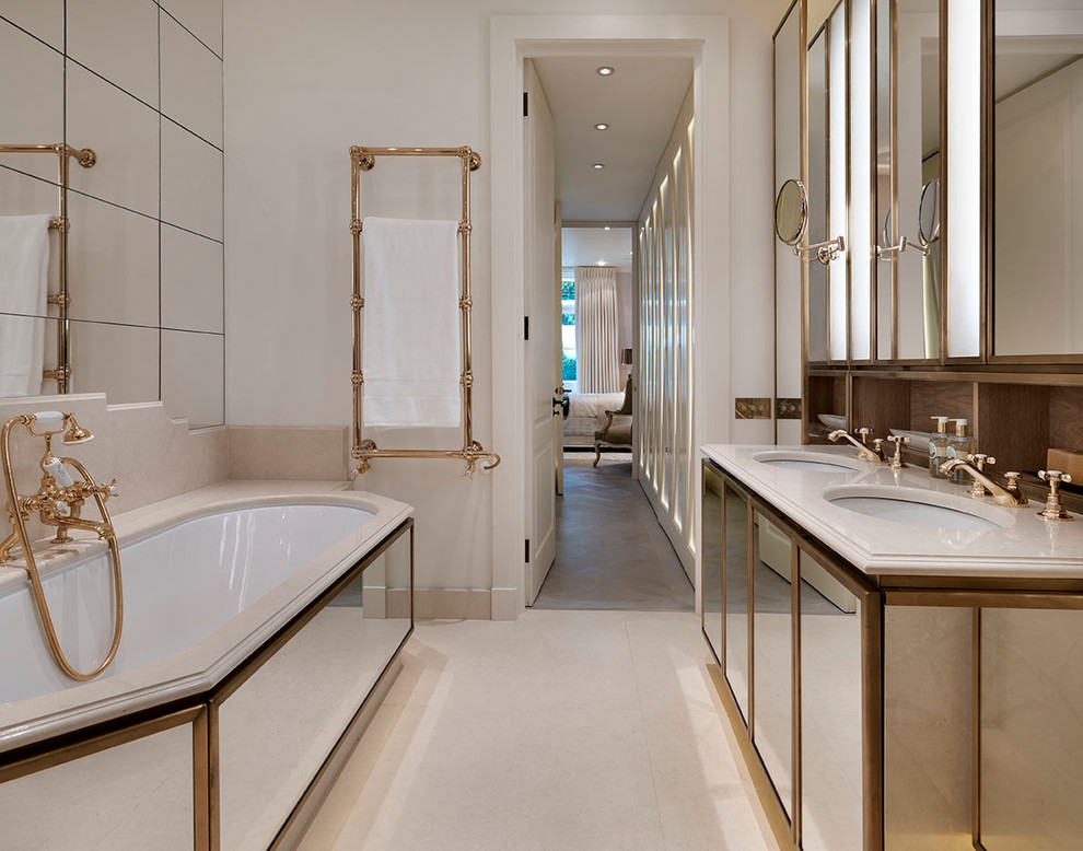 Large traditional master bathroom in London with a drop-in sink, glass-front cabinets, medium wood cabinets, marble benchtops, a drop-in tub, white tile, porcelain tile, white walls and marble floors.