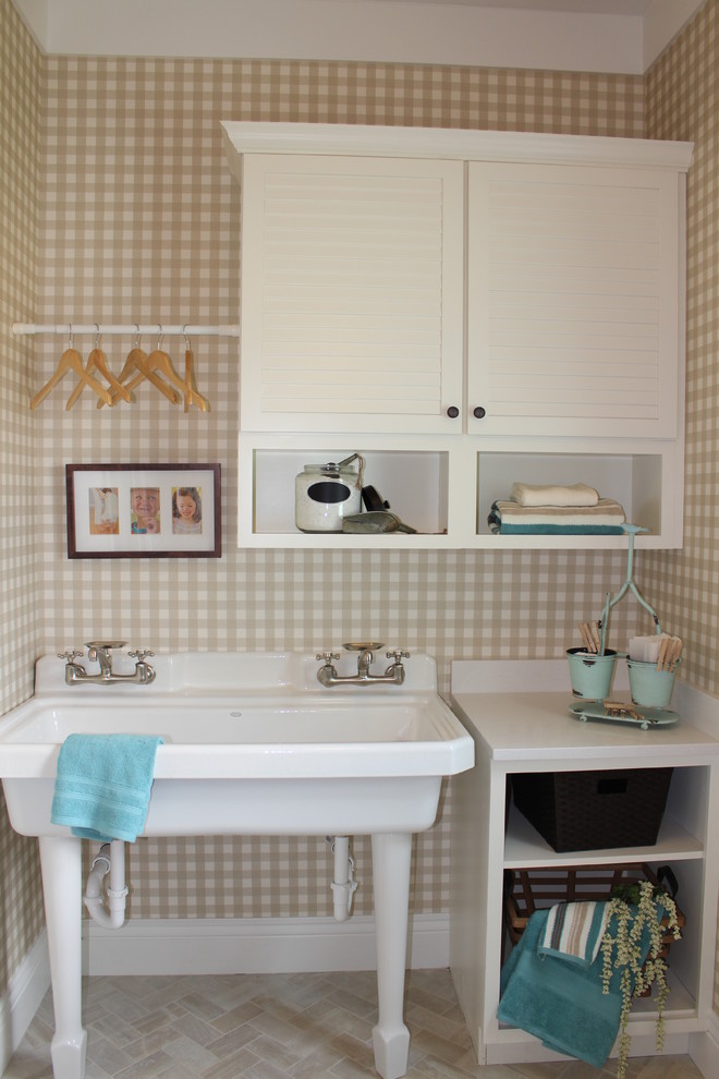 This is an example of a mid-sized transitional single-wall laundry room in Salt Lake City with an utility sink, white cabinets, quartz benchtops, yellow walls, ceramic floors and a side-by-side washer and dryer.