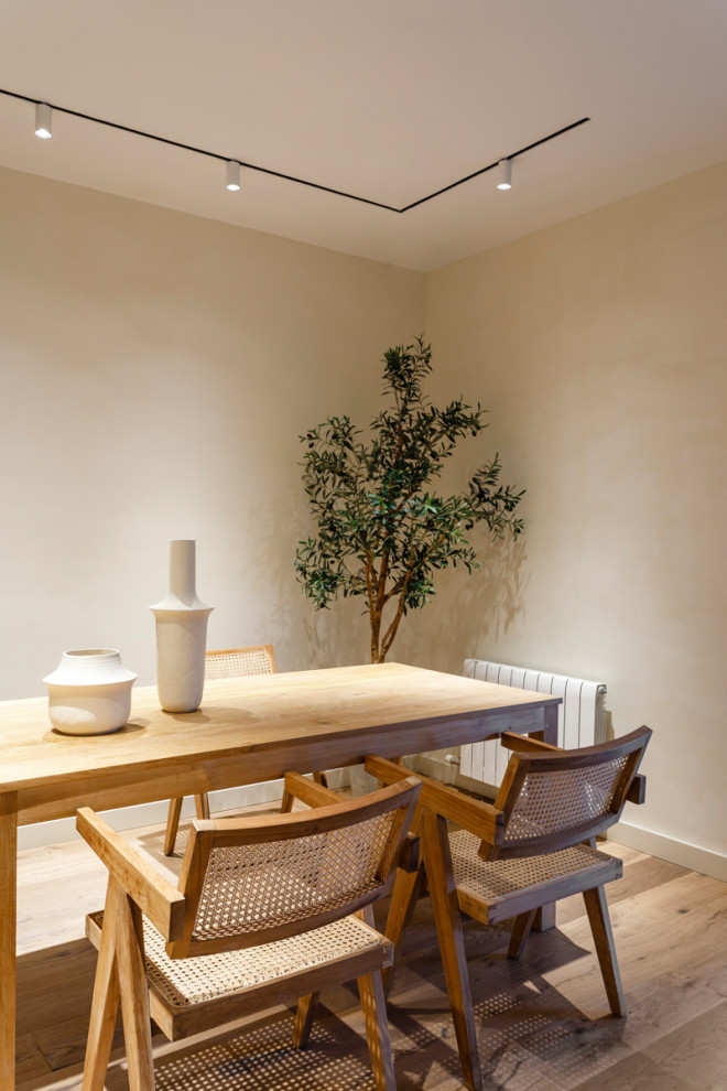 Cette image montre une grande salle à manger ouverte sur la cuisine minimaliste avec un mur beige, sol en stratifié et un sol marron.
