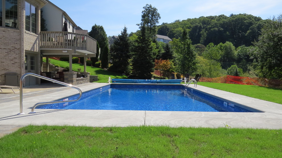Example of a large minimalist backyard stamped concrete and rectangular pool design