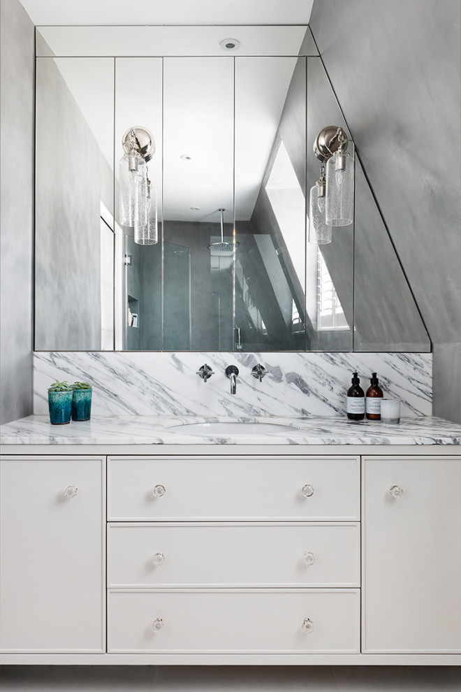 Inspiration for a transitional bathroom in London with green cabinets and marble benchtops.