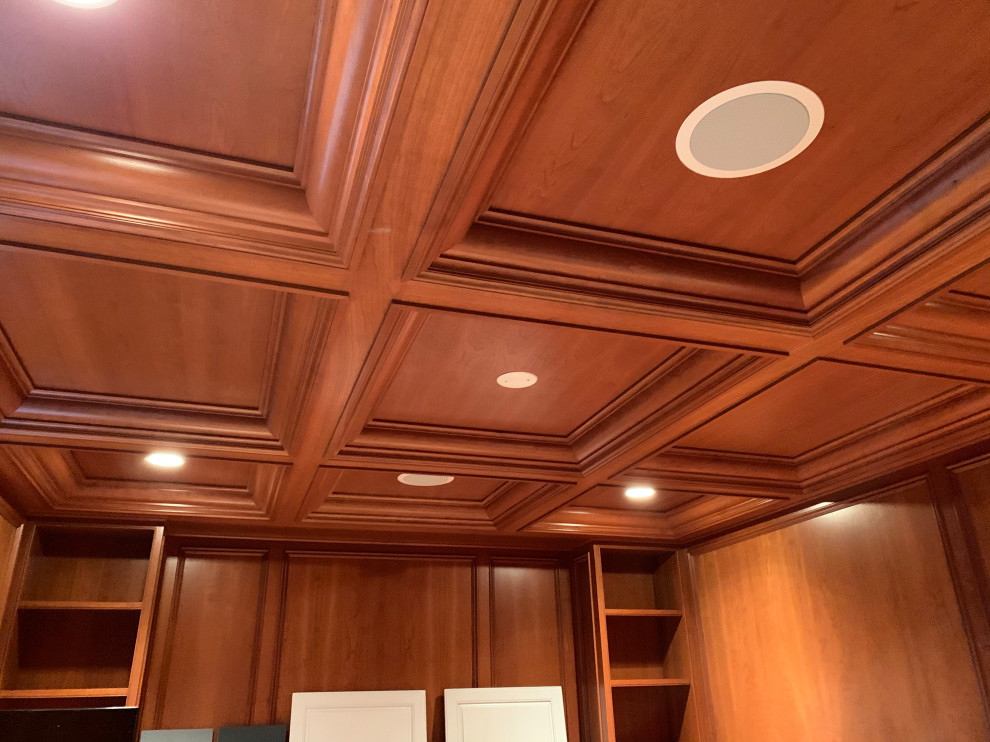 Mittelgroßes Modernes Arbeitszimmer mit grauer Wandfarbe, braunem Holzboden, Kamin, Kaminumrandung aus Stein, Einbau-Schreibtisch, braunem Boden, Kassettendecke und Wandpaneelen in New York