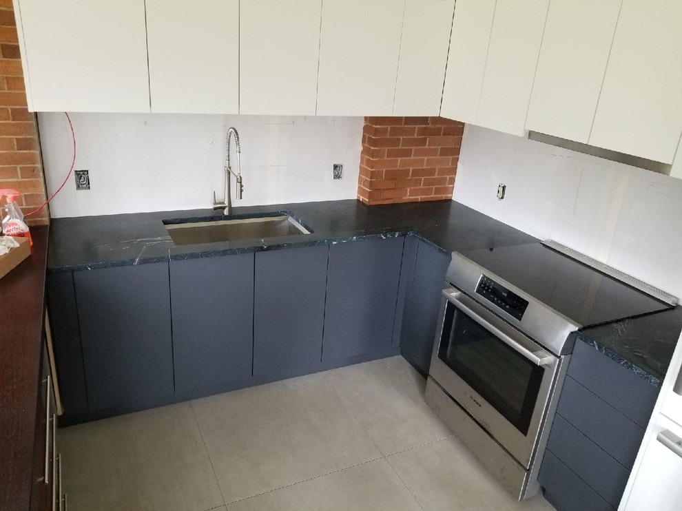 Eat-in kitchen - modern u-shaped ceramic tile and beige floor eat-in kitchen idea with an undermount sink, flat-panel cabinets, white cabinets, soapstone countertops, stainless steel appliances, a peninsula and black countertops