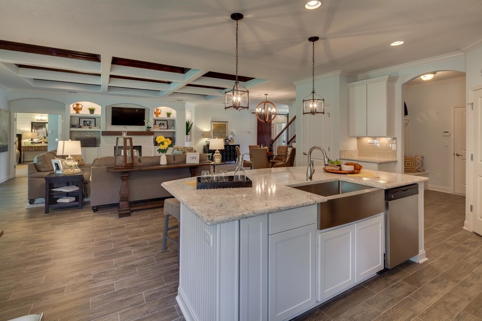 Photo of a large transitional l-shaped eat-in kitchen in Jacksonville with a farmhouse sink, shaker cabinets, white cabinets, granite benchtops, stainless steel appliances, laminate floors and with island.