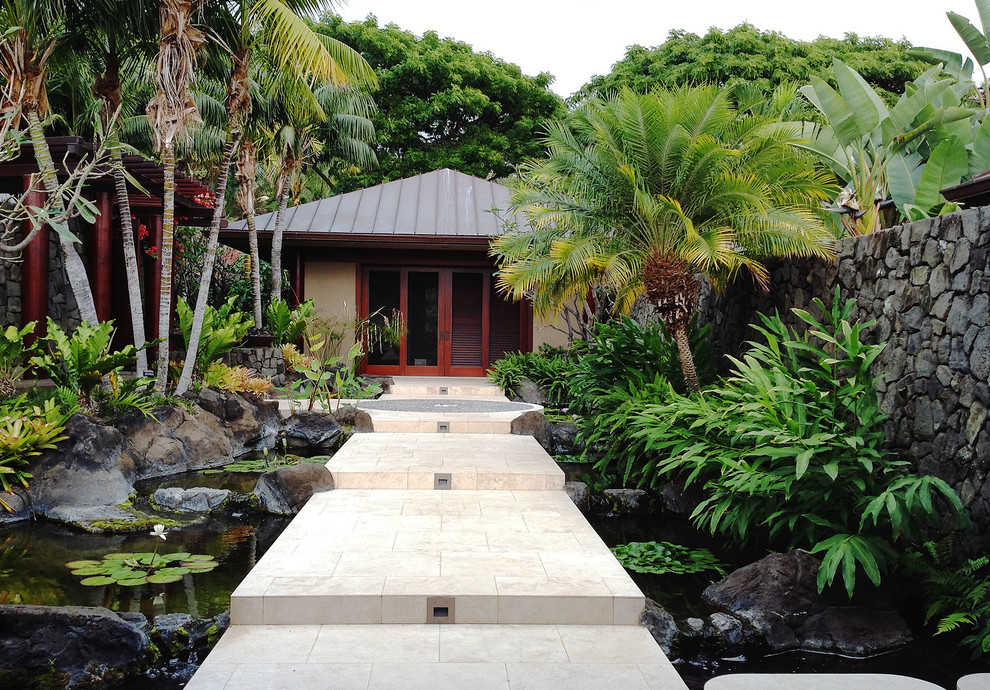 This is an example of a large tropical courtyard partial sun garden in Hawaii with natural stone pavers and with pond.
