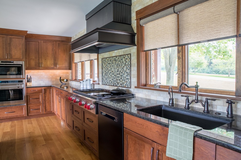 Large mountain style galley light wood floor and beige floor eat-in kitchen photo in Cedar Rapids with recessed-panel cabinets, medium tone wood cabinets, granite countertops, beige backsplash, stone tile backsplash, black appliances, an island, an undermount sink and black countertops