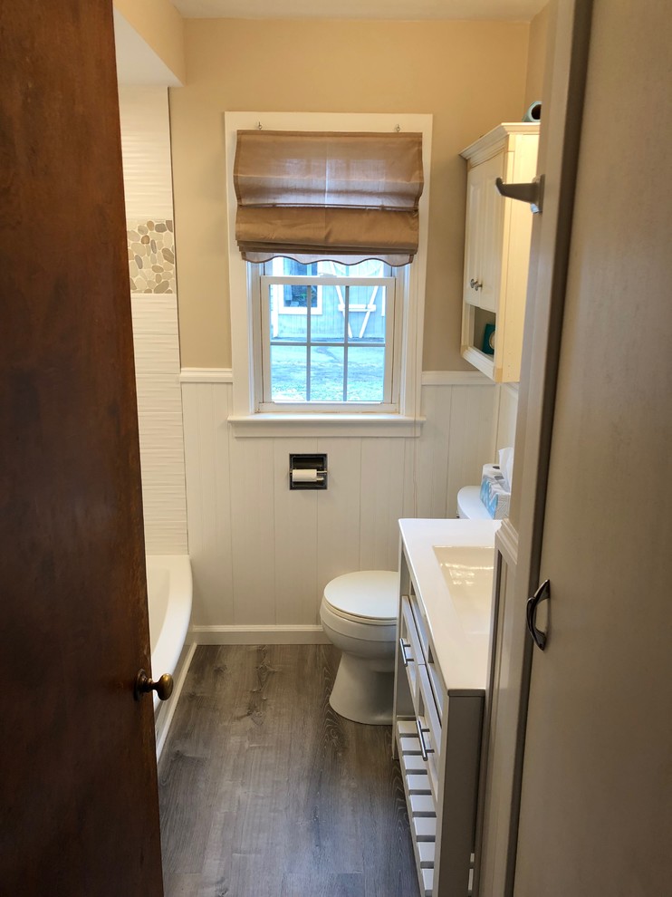 Design ideas for a mid-sized beach style bathroom in New York with furniture-like cabinets, white cabinets, an alcove tub, a shower/bathtub combo, a two-piece toilet, white tile, porcelain tile, beige walls, vinyl floors, an integrated sink, glass benchtops, grey floor, an open shower and white benchtops.