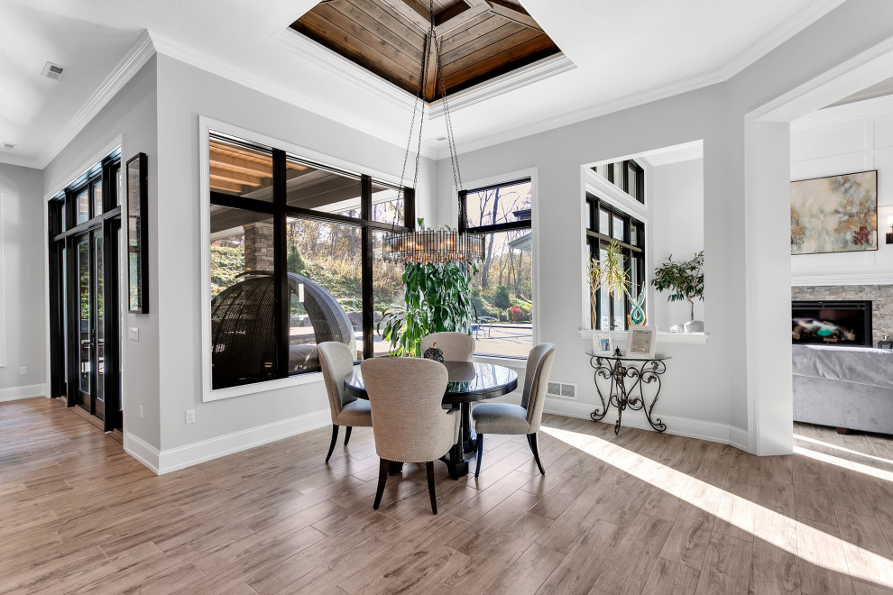 Expansive modern kitchen/dining combo in Other with grey walls, ceramic floors, a standard fireplace, a stone fireplace surround, grey floor, coffered and panelled walls.