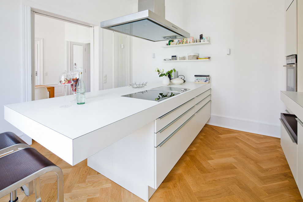Mid-sized scandinavian separate kitchen in Frankfurt with flat-panel cabinets, white cabinets, light hardwood floors, stainless steel appliances and a peninsula.