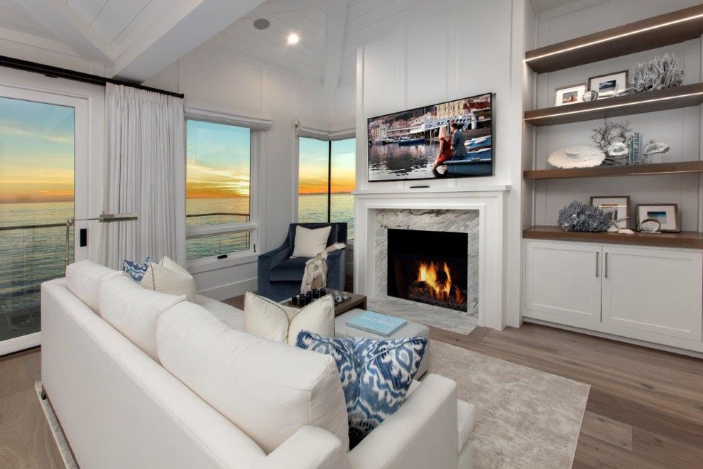 Large beach style master bedroom in Orange County with white walls, dark hardwood floors, a standard fireplace, a stone fireplace surround and brown floor.