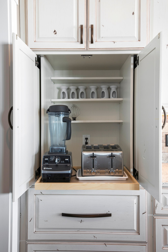 Inspiration for a large transitional l-shaped medium tone wood floor and brown floor eat-in kitchen remodel with an undermount sink, raised-panel cabinets, quartz countertops, beige backsplash, stone tile backsplash, stainless steel appliances, an island and beige countertops