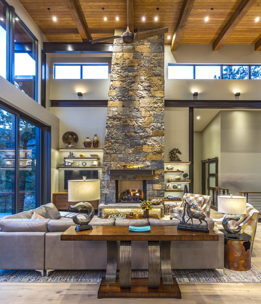 Living room - rustic medium tone wood floor and brown floor living room idea in Kansas City with gray walls, a standard fireplace, a stone fireplace and a wall-mounted tv