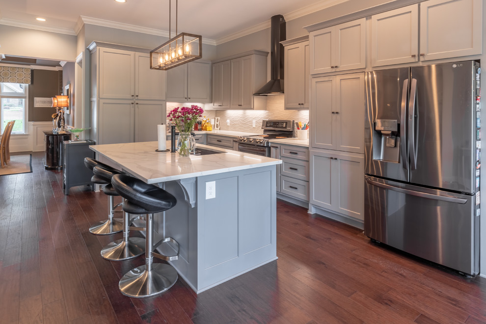 Inspiration for a mid-sized transitional single-wall dark wood floor and brown floor open concept kitchen remodel in Raleigh with an undermount sink, shaker cabinets, gray cabinets, marble countertops, white backsplash, stainless steel appliances, an island and gray countertops