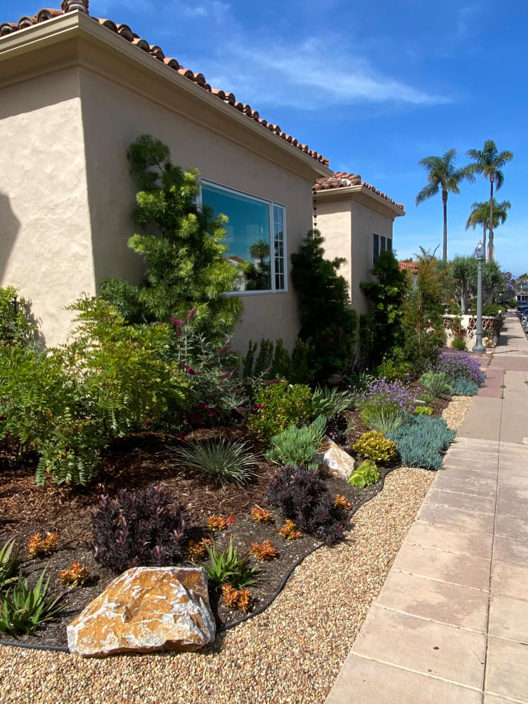 This is an example of a small mediterranean front xeriscape partial sun garden in San Diego with gravel.