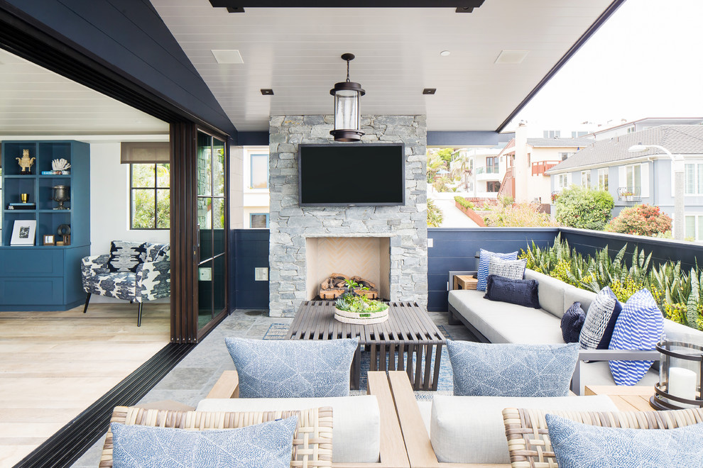 Inspiration for a beach style deck in Orange County with with fireplace and a roof extension.