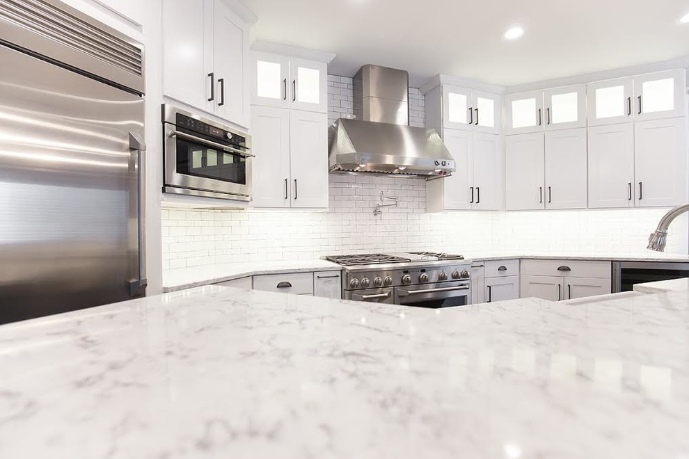Inspiration for a large transitional medium tone wood floor eat-in kitchen remodel with an undermount sink, shaker cabinets, white cabinets, quartzite countertops, white backsplash, subway tile backsplash, stainless steel appliances and an island