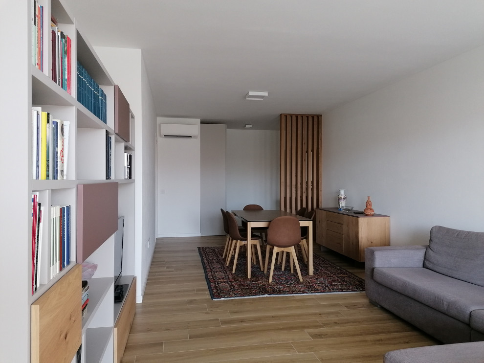 Immagine di un soggiorno design di medie dimensioni e aperto con libreria, pareti bianche, pavimento in gres porcellanato, parete attrezzata e pavimento beige