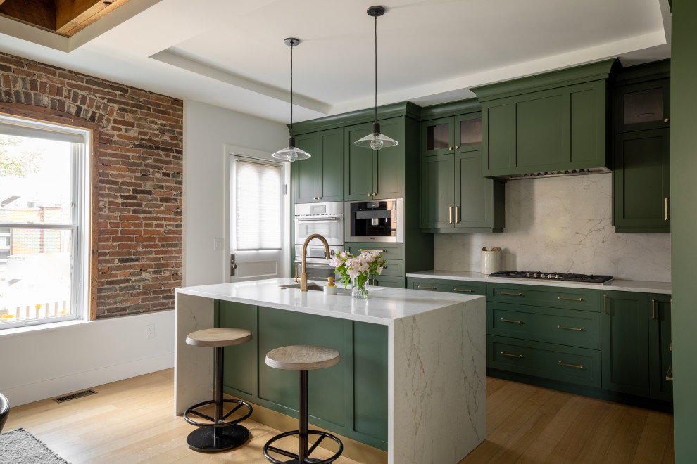 Photo of a large transitional l-shaped eat-in kitchen in Detroit with an undermount sink, shaker cabinets, green cabinets, white splashback, stainless steel appliances, with island, brown floor, white benchtop, recessed, quartz benchtops, engineered quartz splashback and light hardwood floors.