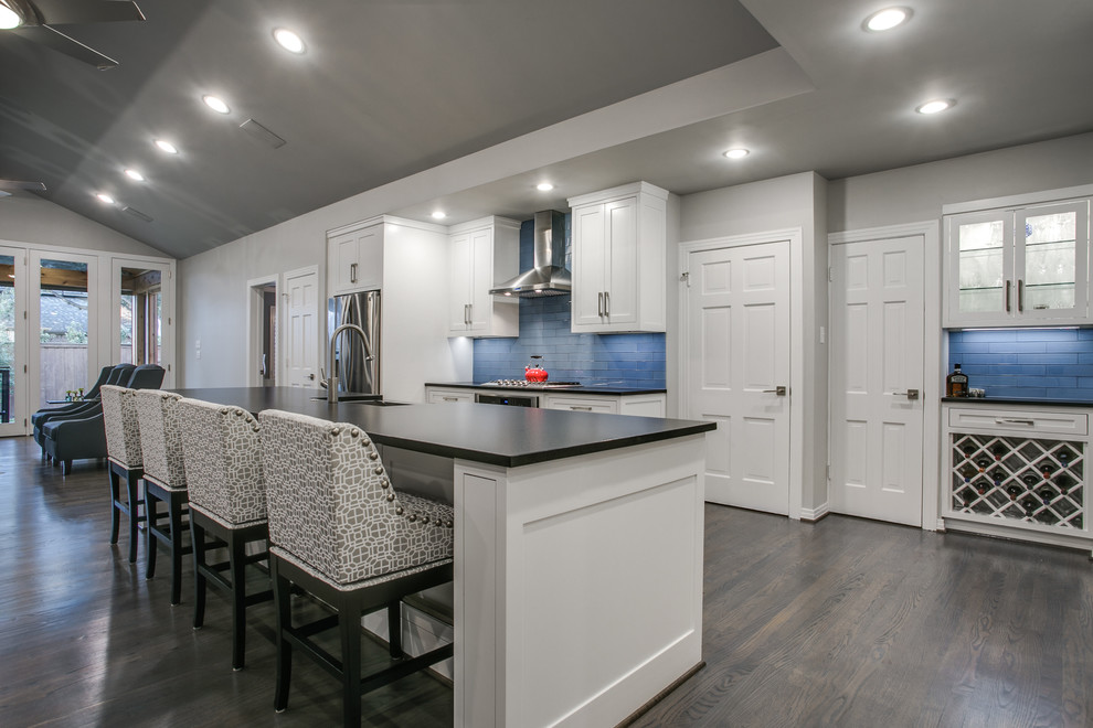 Inspiration for a large transitional l-shaped dark wood floor open concept kitchen remodel in Dallas with a farmhouse sink, shaker cabinets, white cabinets, quartz countertops, blue backsplash, subway tile backsplash, stainless steel appliances and an island