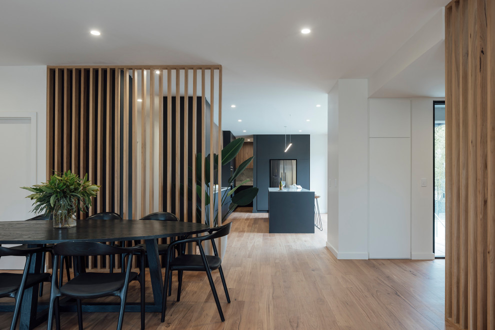 Inspiration pour une grande salle à manger ouverte sur le salon design avec un mur blanc et un sol en bois brun.