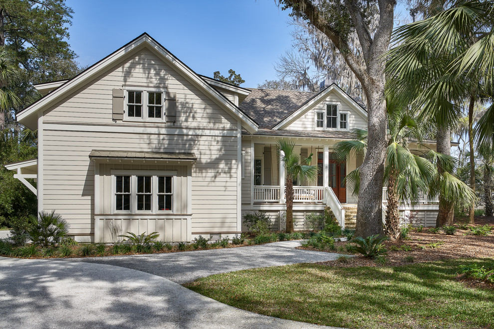 Photo of a large beach style two-storey beige house exterior in Charleston with a shingle roof and wood siding.