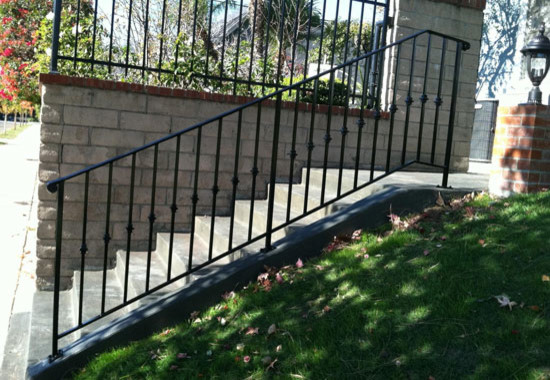 Inspiration for a small modern front yard shaded driveway for fall in Los Angeles with concrete pavers and a metal fence.