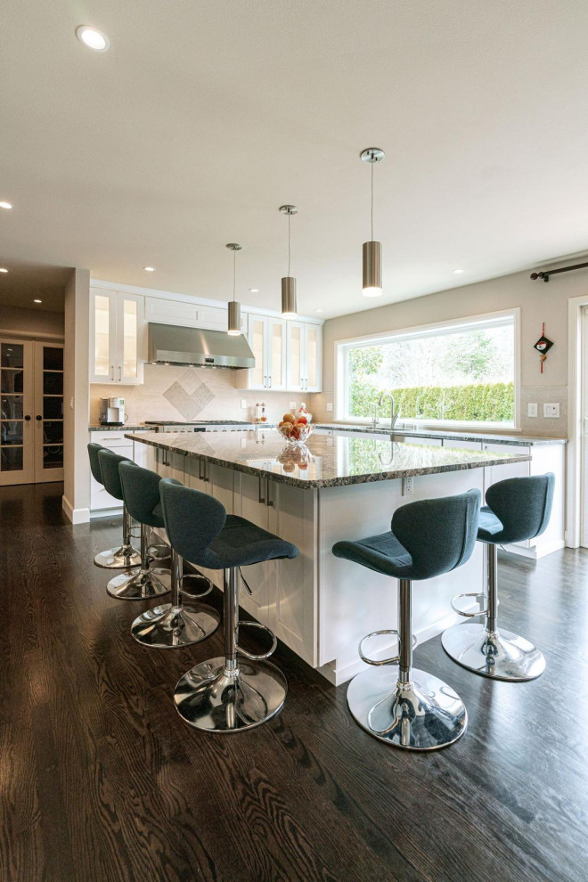 Large transitional l-shaped eat-in kitchen photo in Seattle with a drop-in sink, glass-front cabinets, white cabinets, quartzite countertops, beige backsplash, stainless steel appliances, an island and gray countertops