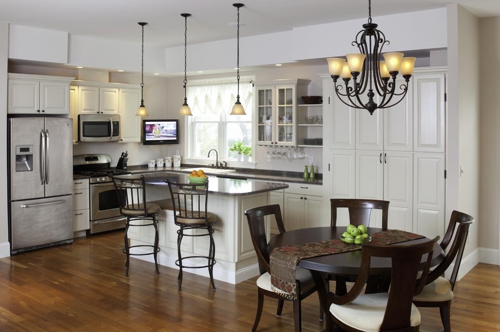 Traditional l-shaped eat-in kitchen in Boston with raised-panel cabinets, white cabinets and stainless steel appliances.