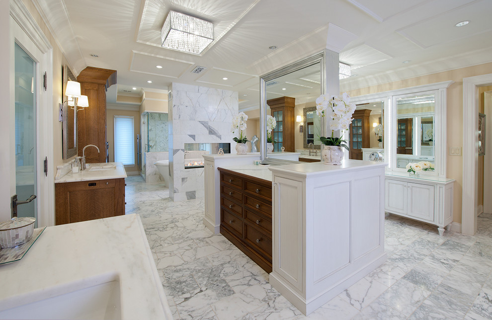 This is an example of an expansive contemporary master bathroom in Other with white cabinets, a freestanding tub, beige walls, marble floors, an undermount sink, marble benchtops, stone tile and recessed-panel cabinets.