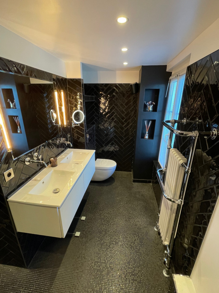 Photo of a mid-sized midcentury 3/4 bathroom in Other with white cabinets, a curbless shower, a wall-mount toilet, black tile, terra-cotta tile, black walls, mosaic tile floors, a wall-mount sink, black floor, a double vanity and a floating vanity.