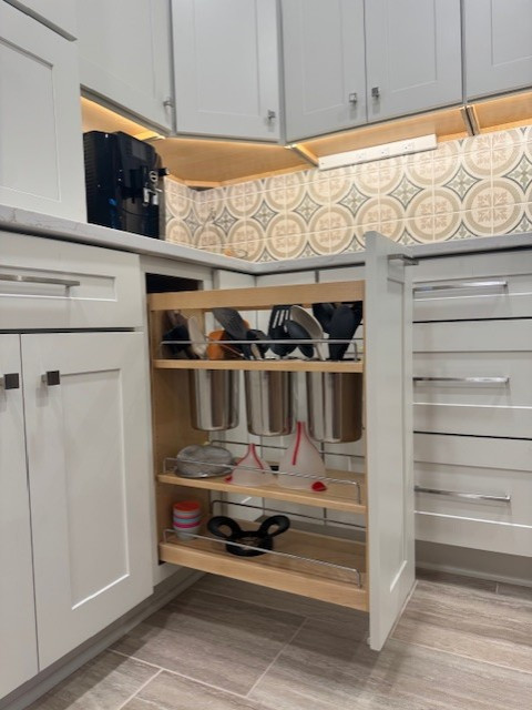 Mid-sized transitional l-shaped porcelain tile and beige floor eat-in kitchen photo with recessed-panel cabinets, white cabinets, quartz countertops, beige backsplash, porcelain backsplash, stainless steel appliances, an island and white countertops