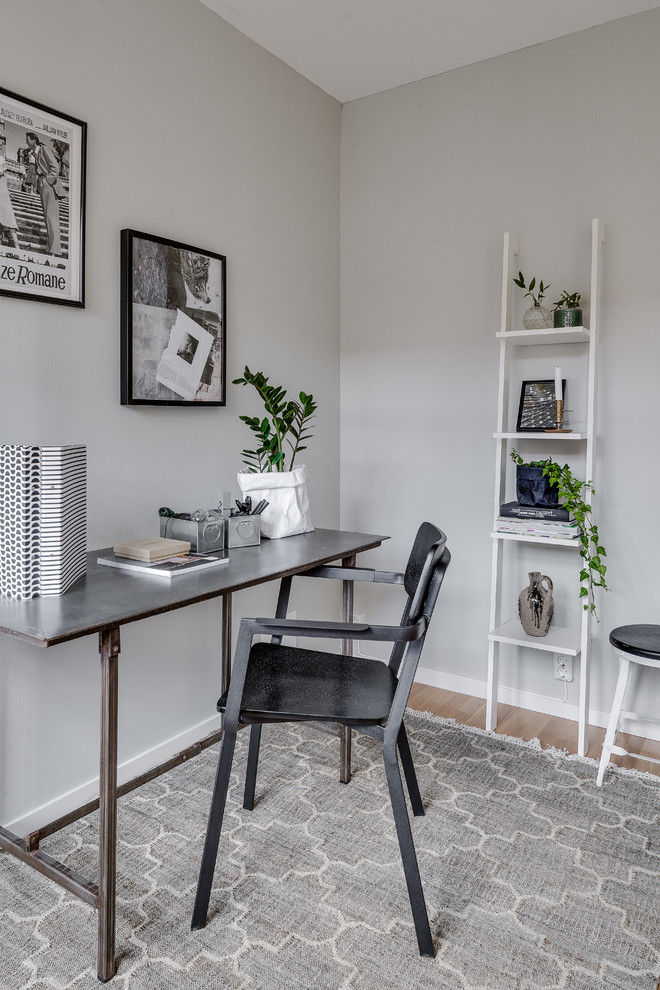 Inspiration for a mid-sized scandinavian study room in Gothenburg with grey walls, light hardwood floors and a freestanding desk.