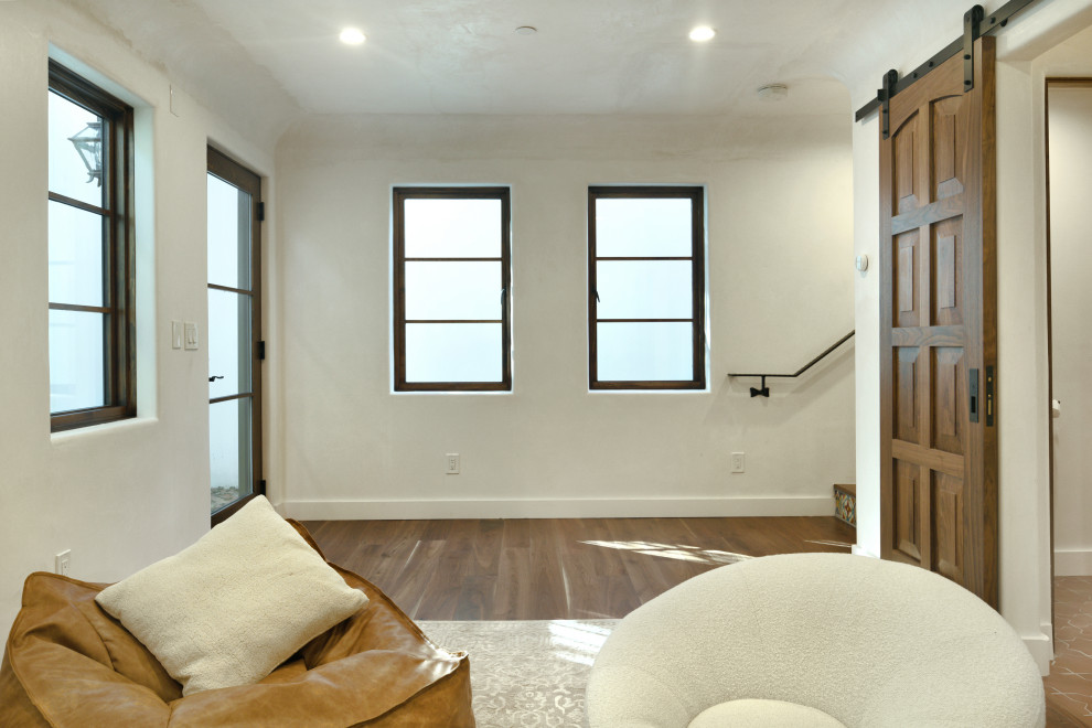 Modelo de sala de estar abierta mediterránea de tamaño medio con suelo de madera en tonos medios, suelo marrón y televisor colgado en la pared