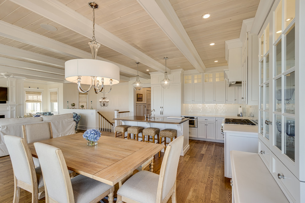 Inspiration for a large beach style eat-in kitchen in Philadelphia with a farmhouse sink, flat-panel cabinets, white cabinets, wood benchtops, white splashback, ceramic splashback, panelled appliances, medium hardwood floors, with island and brown floor.