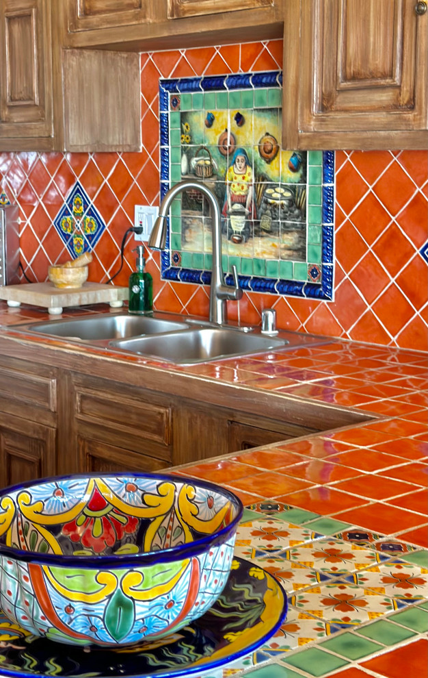 Photo of a medium sized mediterranean u-shaped kitchen/diner in Other with raised-panel cabinets, medium wood cabinets, tile countertops, orange splashback, terracotta splashback, terracotta flooring, a breakfast bar, brown floors, orange worktops and exposed beams.