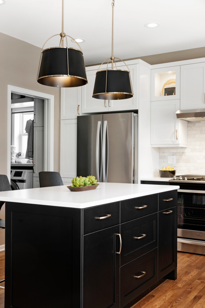 Mid-sized transitional l-shaped medium tone wood floor and brown floor eat-in kitchen photo in Minneapolis with an undermount sink, recessed-panel cabinets, black cabinets, quartz countertops, beige backsplash, stone tile backsplash, stainless steel appliances, an island and white countertops