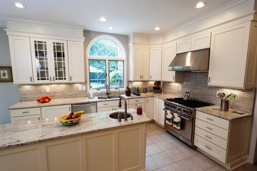 This is an example of a large transitional l-shaped eat-in kitchen in DC Metro with a double-bowl sink, shaker cabinets, white cabinets, granite benchtops, multi-coloured splashback, stainless steel appliances, ceramic floors, with island, stone slab splashback and beige floor.