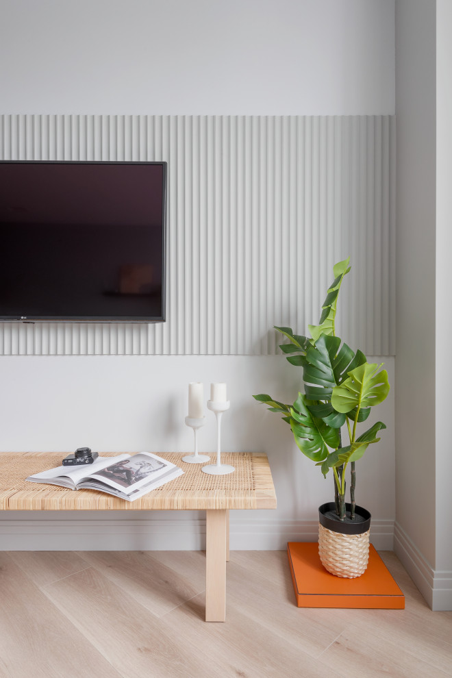 На фото: серо-белая гостиная комната в современном стиле с серыми стенами, полом из ламината, телевизором на стене, бежевым полом и панелями на части стены