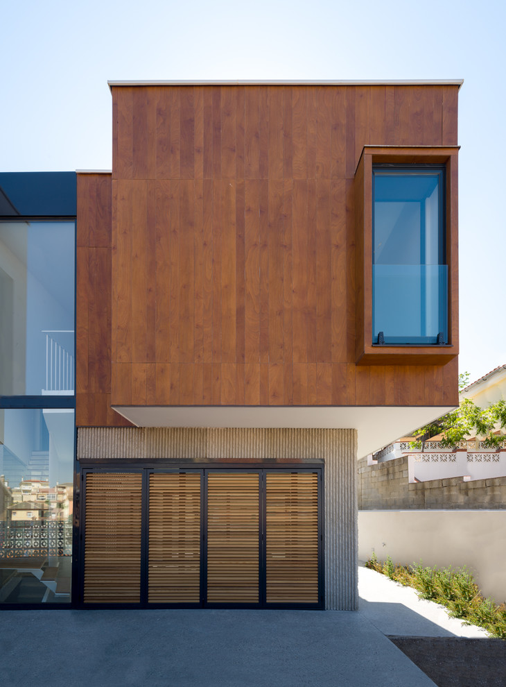 This is an example of a contemporary two-storey brown house exterior in Malaga with mixed siding and a flat roof.