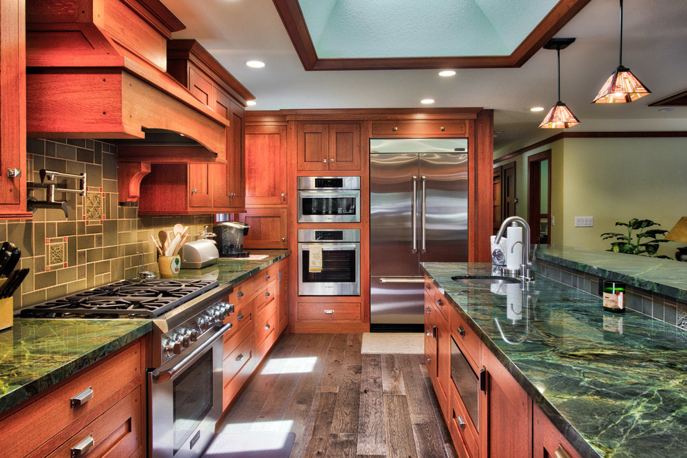 Large arts and crafts u-shaped kitchen in San Francisco with an undermount sink, shaker cabinets, medium wood cabinets, green splashback, ceramic splashback, stainless steel appliances, with island and green benchtop.