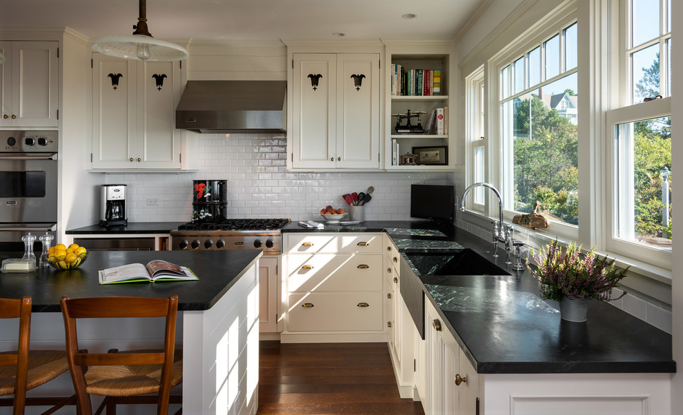 Inspiration for a country l-shaped open plan kitchen in Portland Maine with recessed-panel cabinets, white cabinets, granite benchtops, with island, a farmhouse sink, white splashback, subway tile splashback, stainless steel appliances and dark hardwood floors.